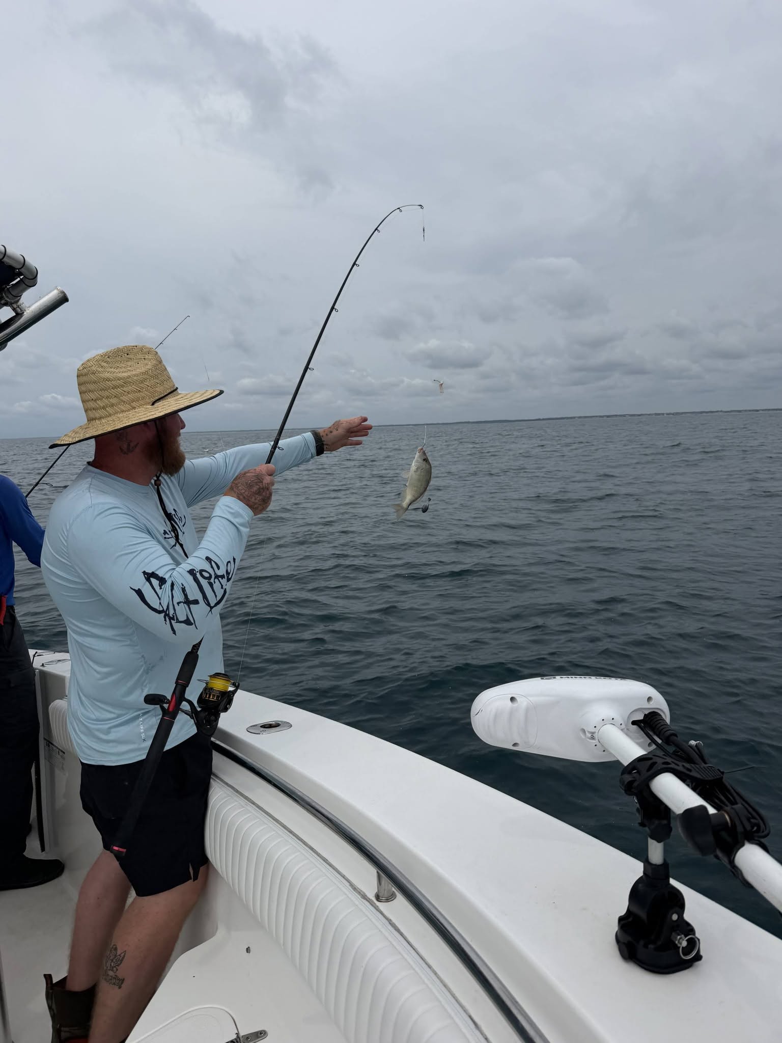Fishing rod bent with caught fish on line over ocean water at Wrightsville Beach NC