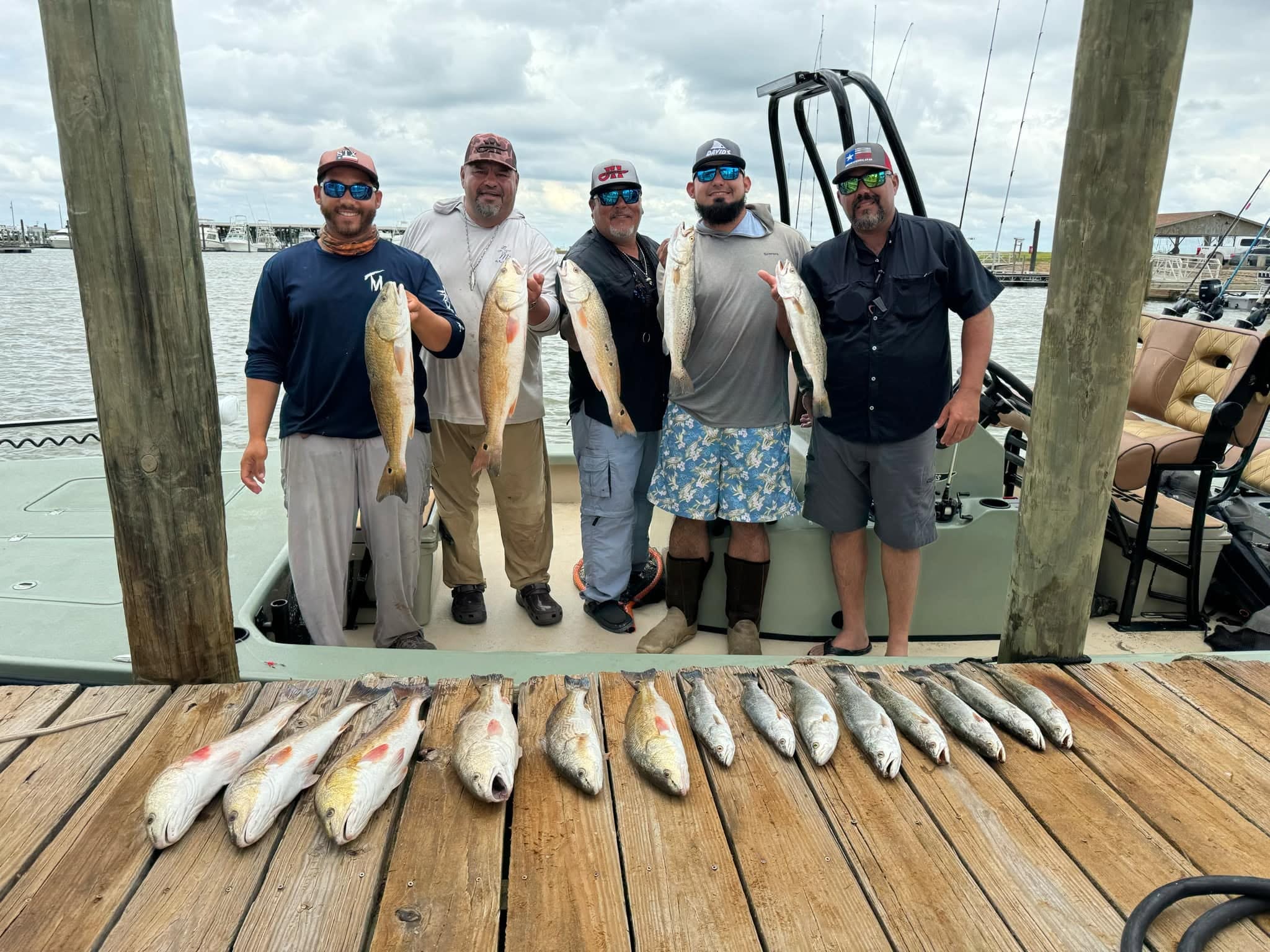 Successful fishing trip in Sargent TX showing caught redfish and speckled trout displayed on dock