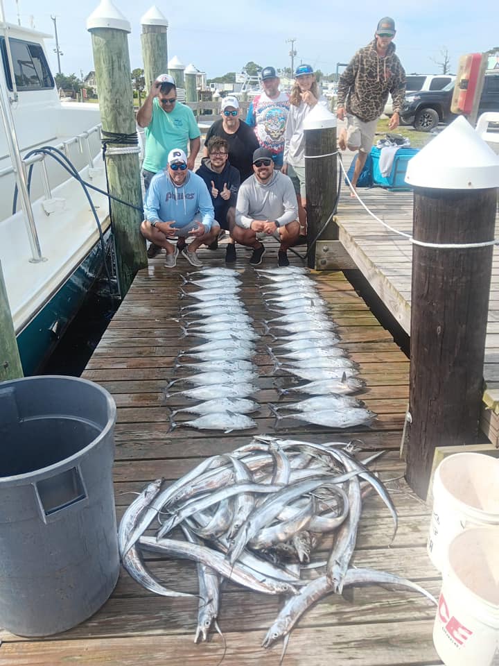 Fresh caught fish displayed on wooden dock in Corolla NC with fishing boat and marina in background