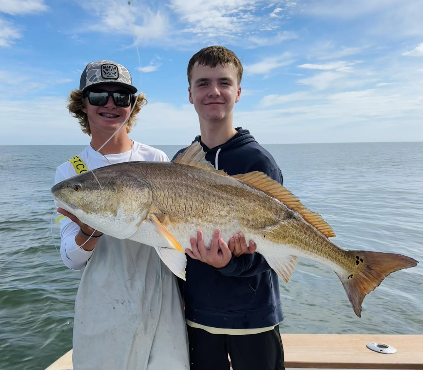 Two anglers holding a large redfish caught while fishing in Corolla NC
