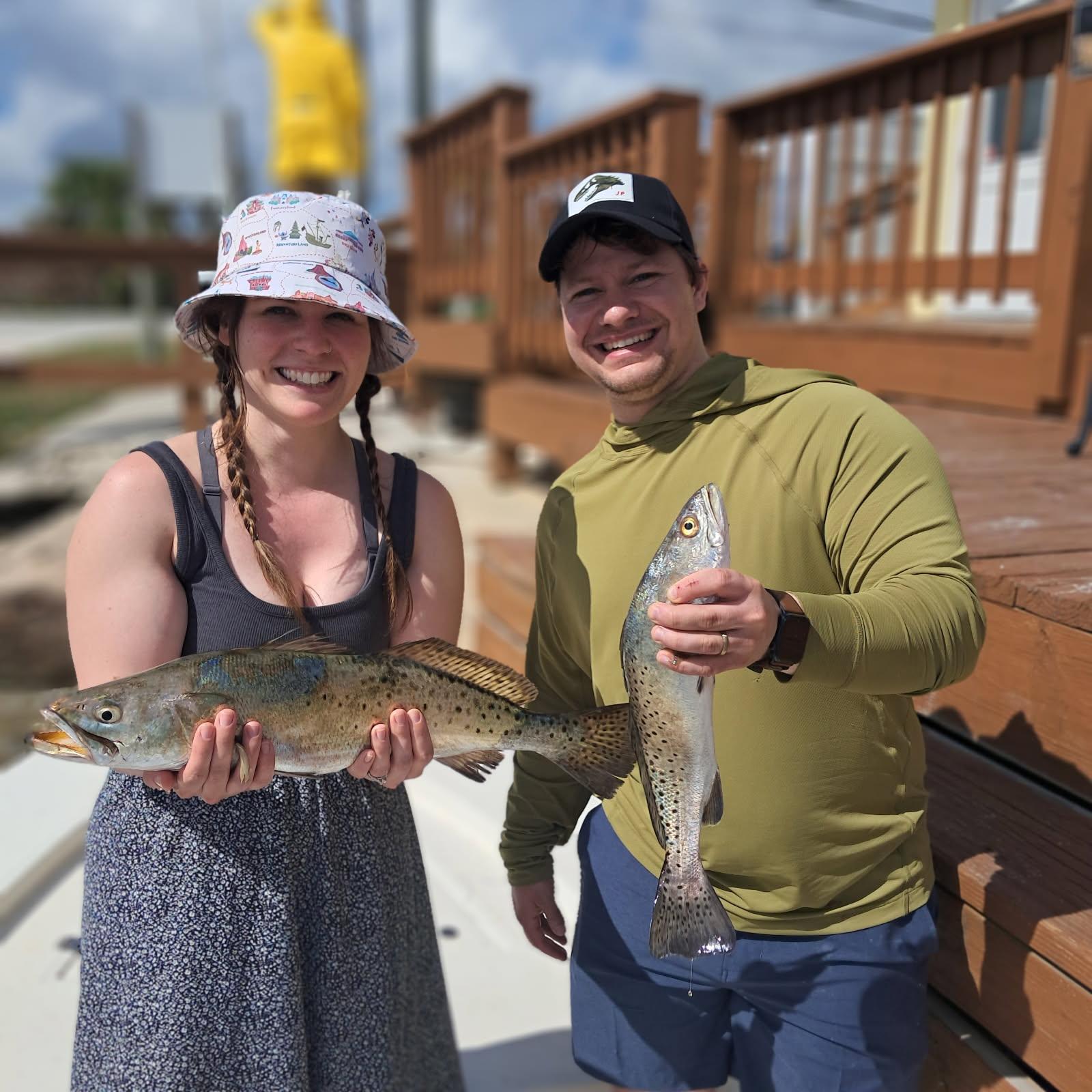 Two anglers holding speckled trout catch on fishing dock in Oak Hill FL