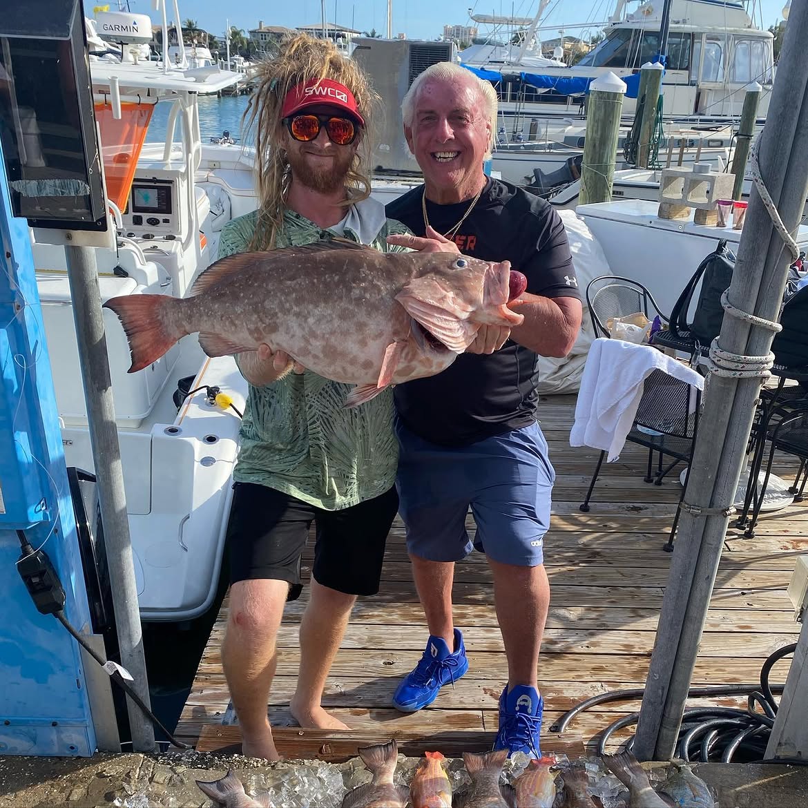 Two anglers displaying a large red grouper catch at marina dock in Clearwater FL