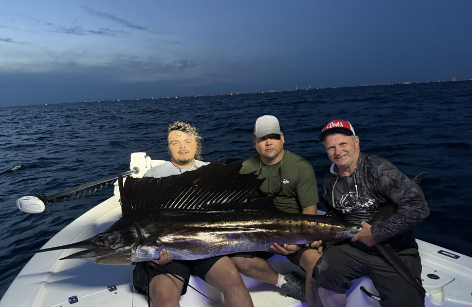 Three anglers on boat holding large Atlantic sailfish caught while fishing in Panama City FL waters