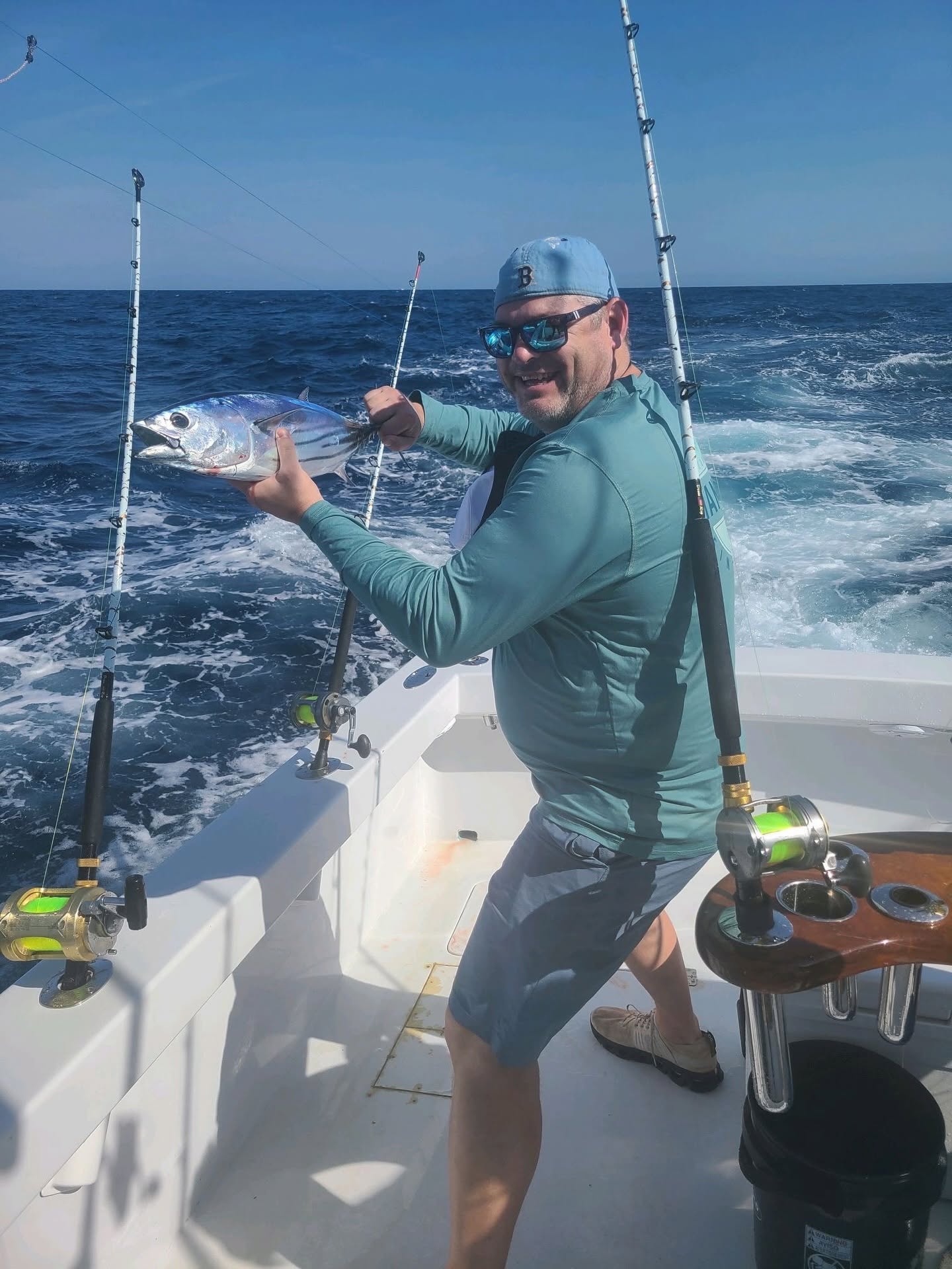 Angler holding caught fish on fishing boat in Charleston SC waters with multiple fishing rods visible