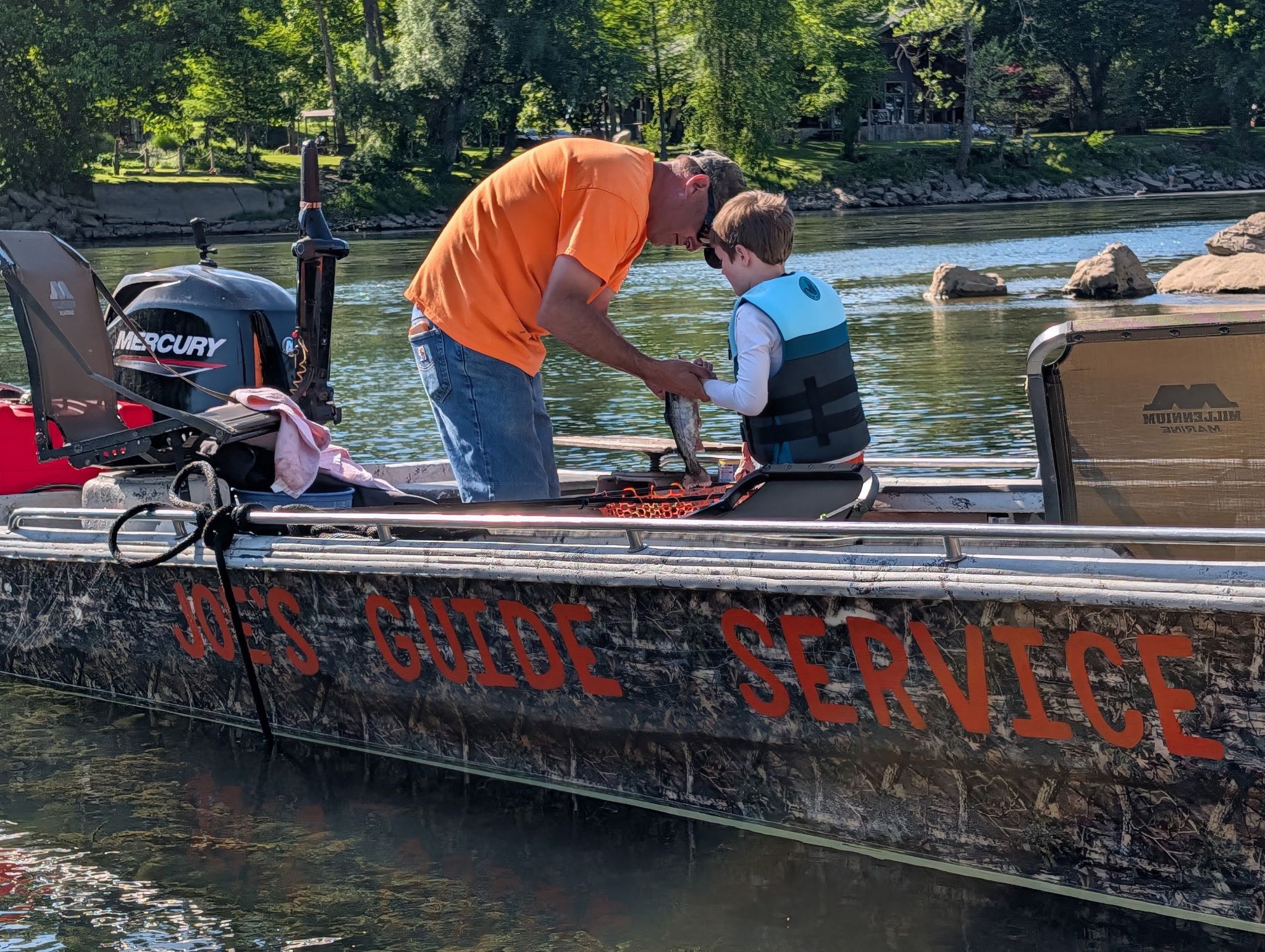Fishing guide boat with guide service text on hull docked at Cotter Arkansas waterway