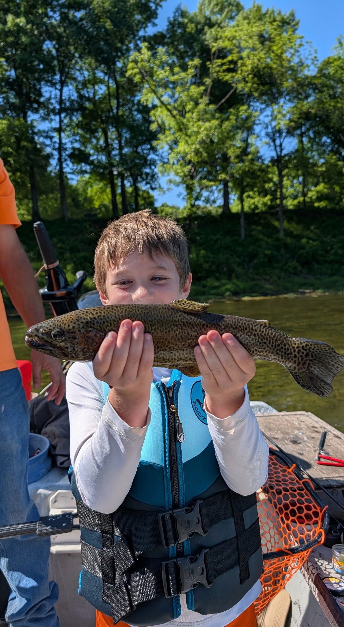 Young angler holding freshly caught trout on fishing boat in Cotter Arkansas