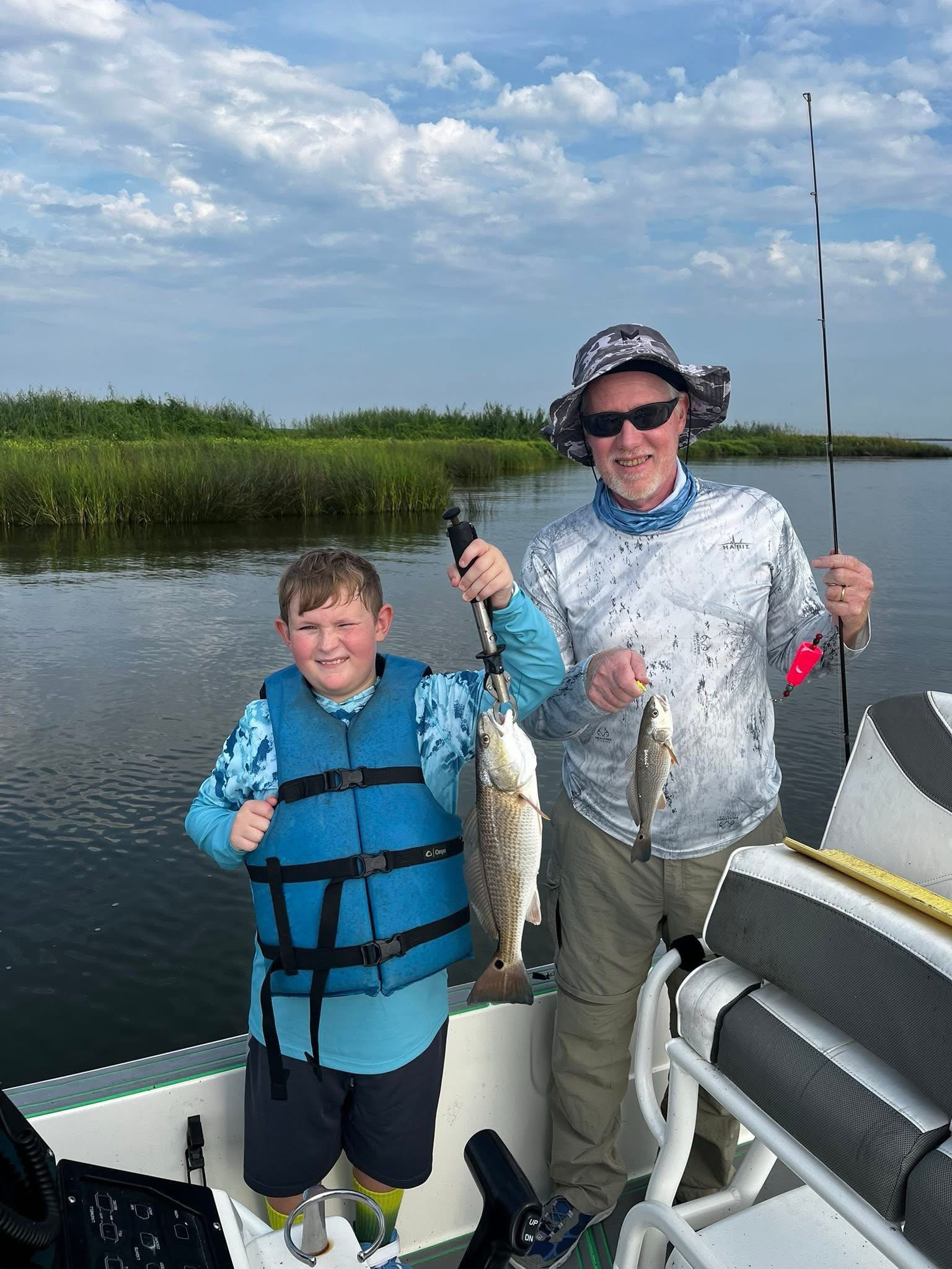 Two redfish caught during fishing trip in St Bernard Louisiana with boat and marsh grass visible