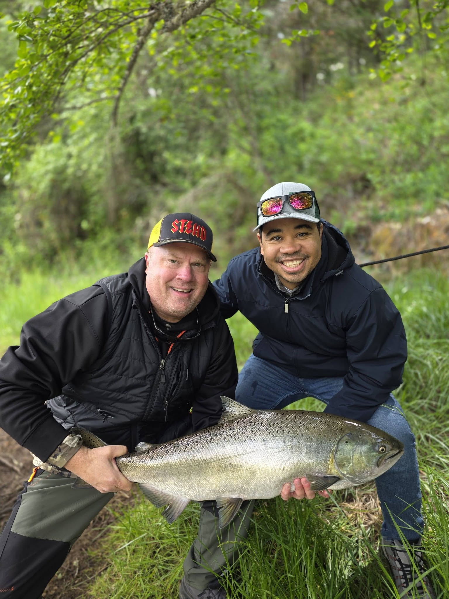 Two anglers holding a large Chinook salmon catch during fishing tour in Central Point OR