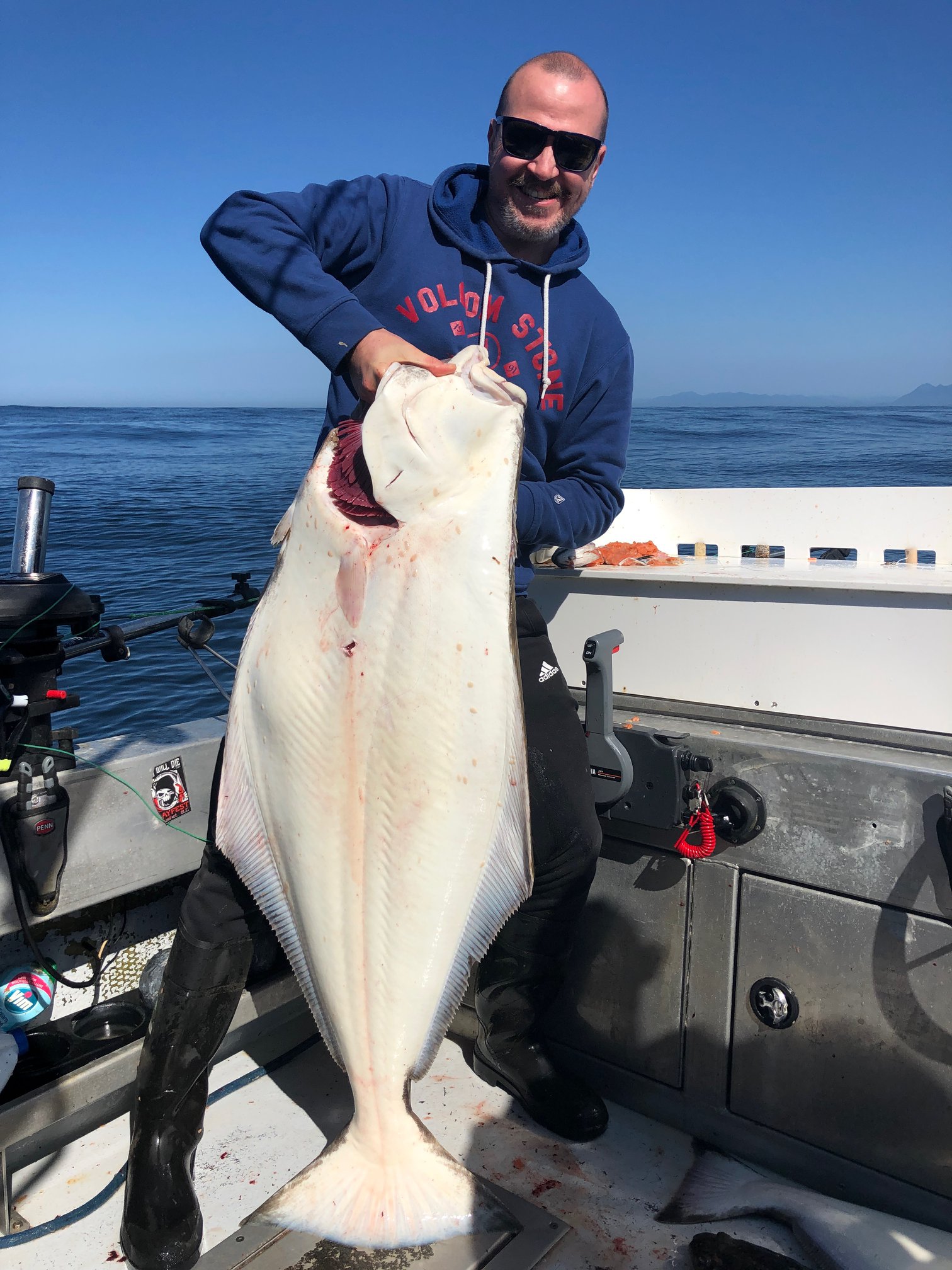 A fisherman holding a large Pacific Halibut in Ucluelet