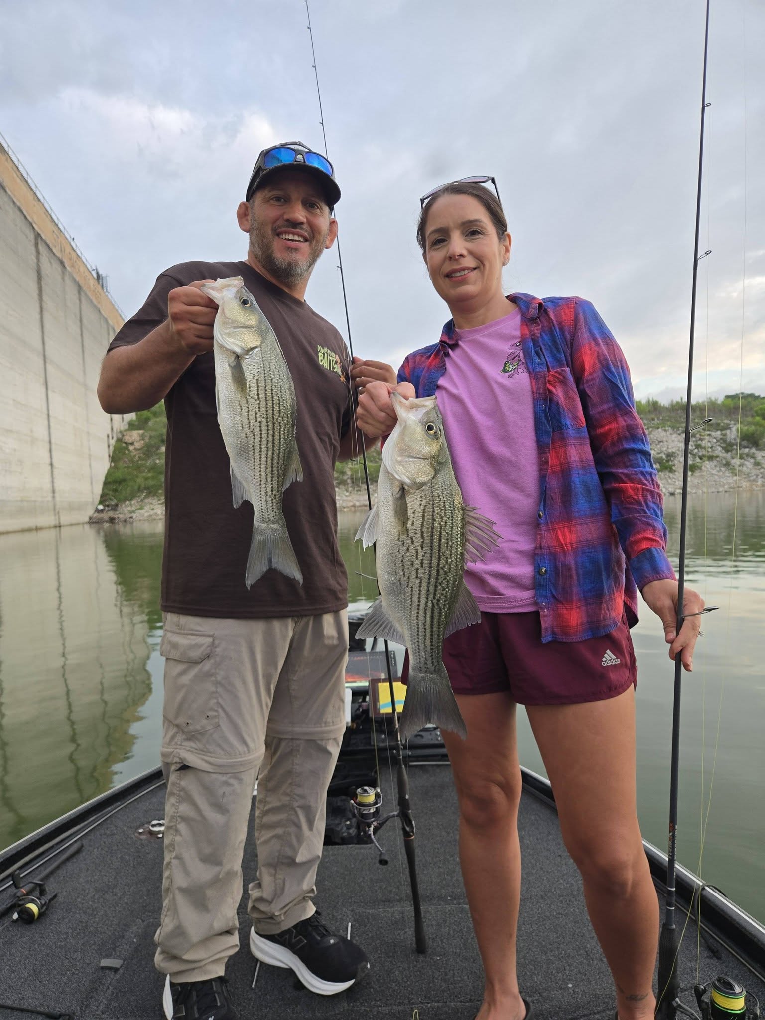 Two anglers displaying freshly caught striped bass on fishing boat in San Antonio TX