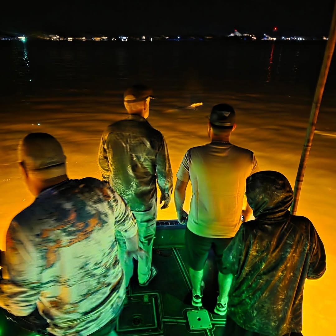 Night fishing scene on boat deck with distant shoreline lights in Ohio