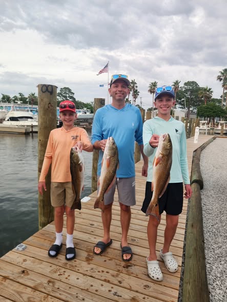Three redfish caught fishing in Shalimar FL displayed on marina dock