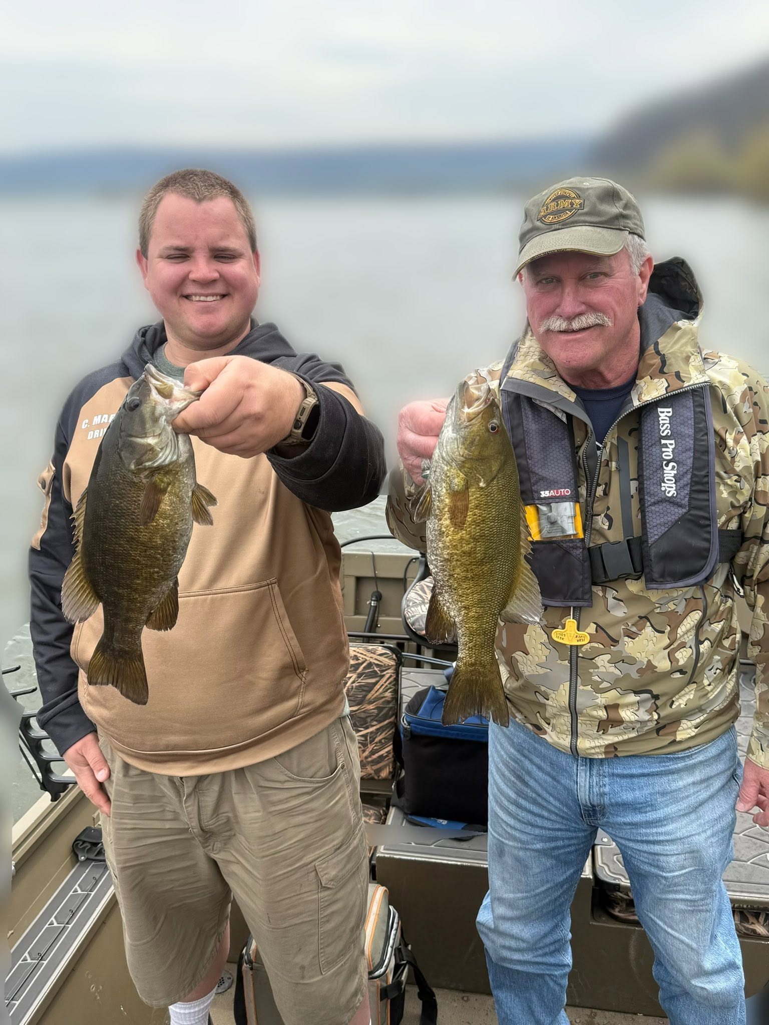 Two anglers holding freshly caught smallmouth bass on fishing boat in Harrisburg PA