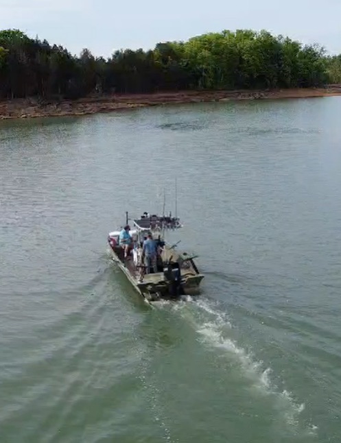 Fishing boat traveling through calm waters near wooded shoreline in Rutledge Tennessee