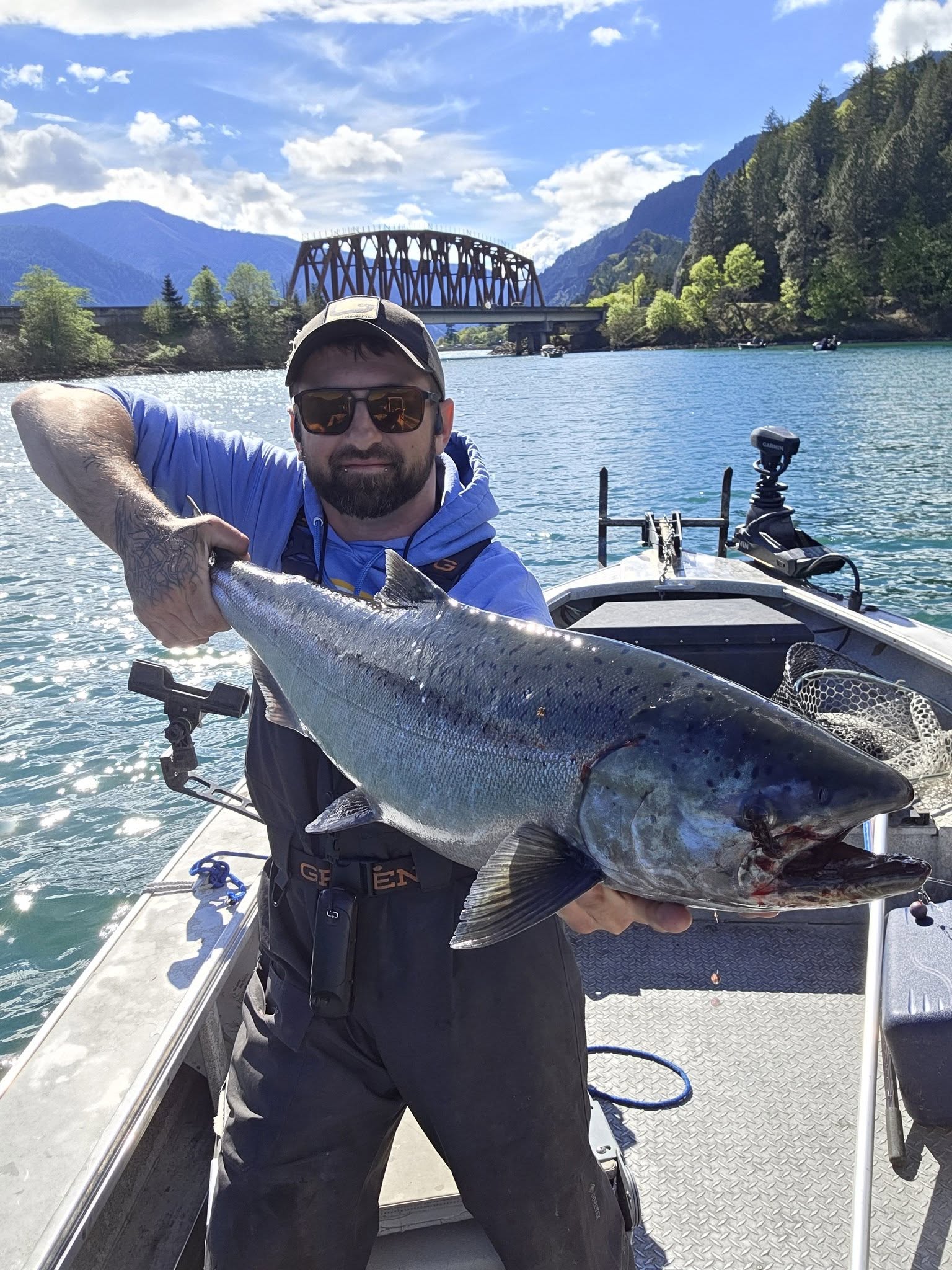 Large Chinook salmon caught while fishing in Dayton WA displayed on fishing boat with bridge and mountains in background