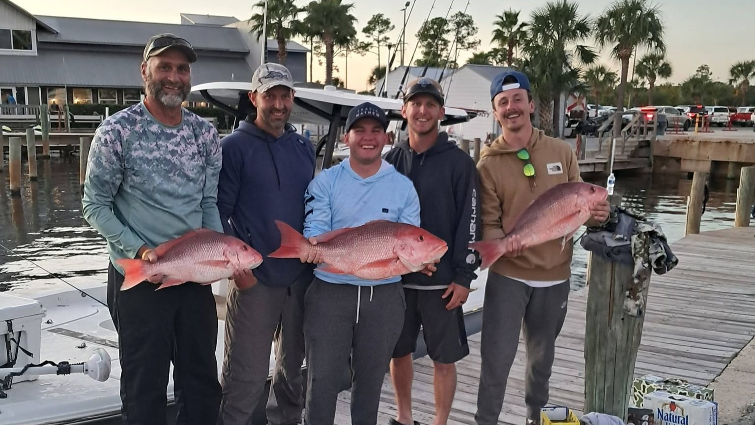 Five anglers displaying red snapper catch on wooden dock at Panama City Beach FL marina