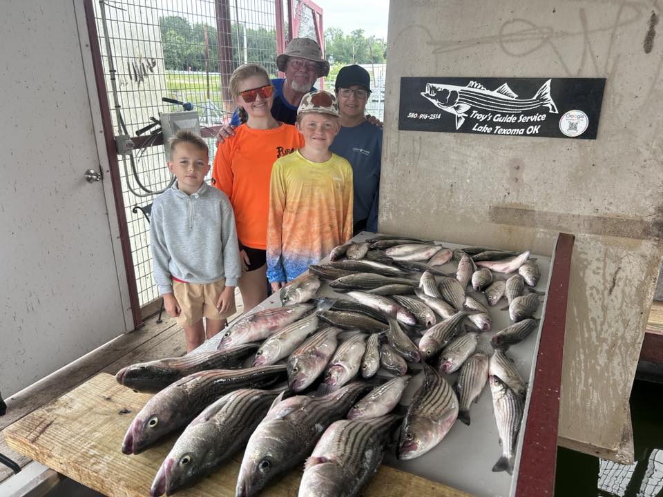 Large catch of striped bass and hybrid stripers displayed on cleaning table at fishing guide service in Madill OK
