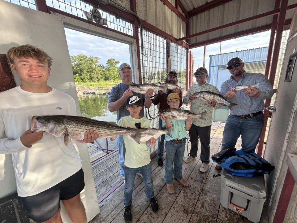 Group fishing trip displaying caught striped bass on dock in Madill OK