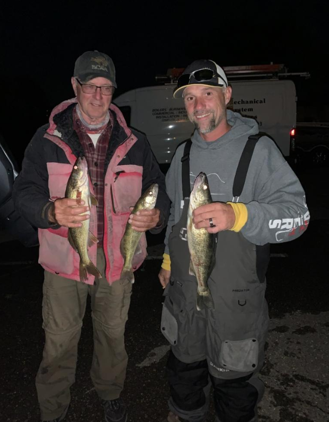 Two anglers displaying fresh caught walleye after successful fishing trip in Harrison Township MI