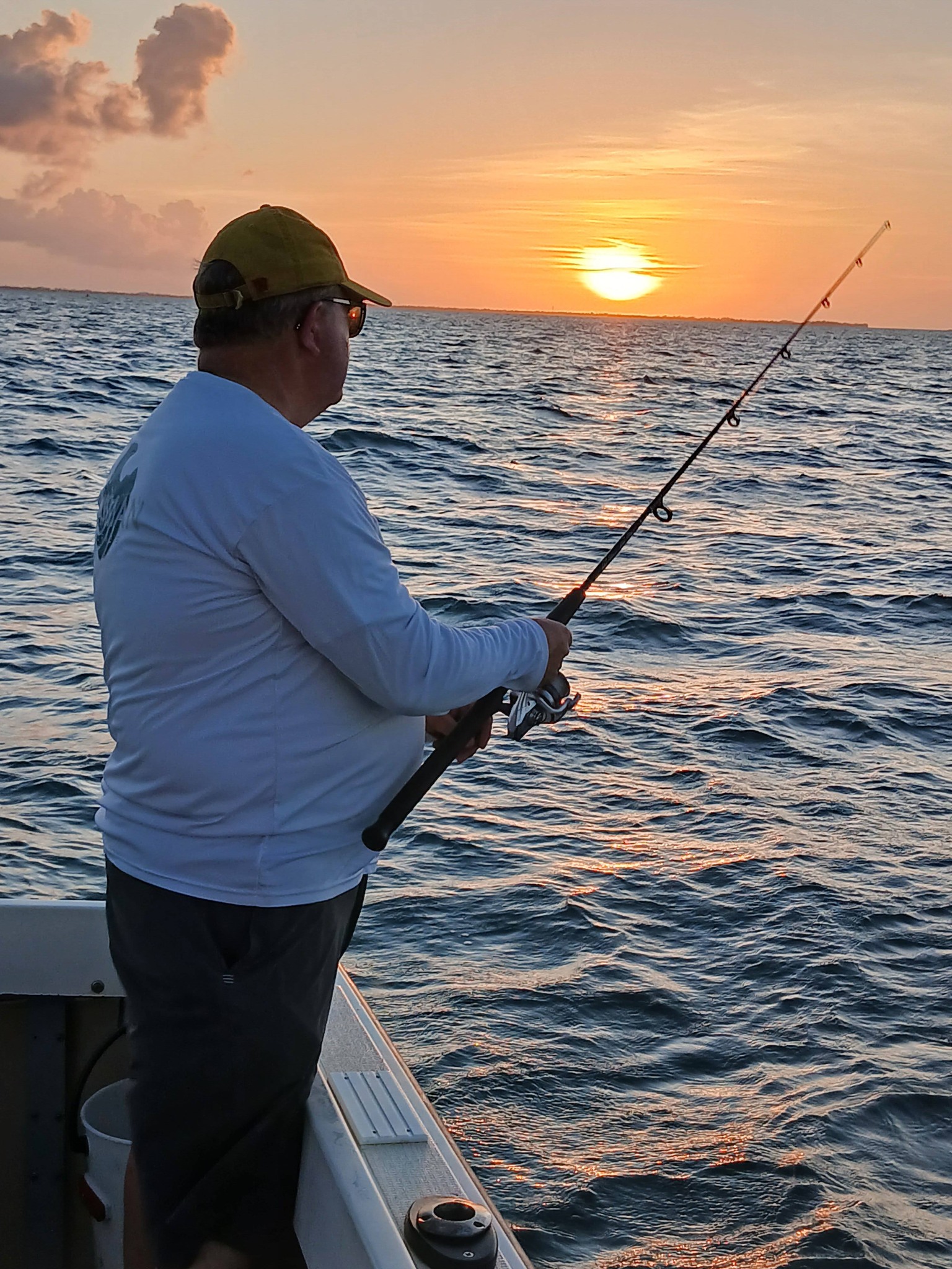 Fishing from boat at sunset in West Bay with rod extended over ocean waters