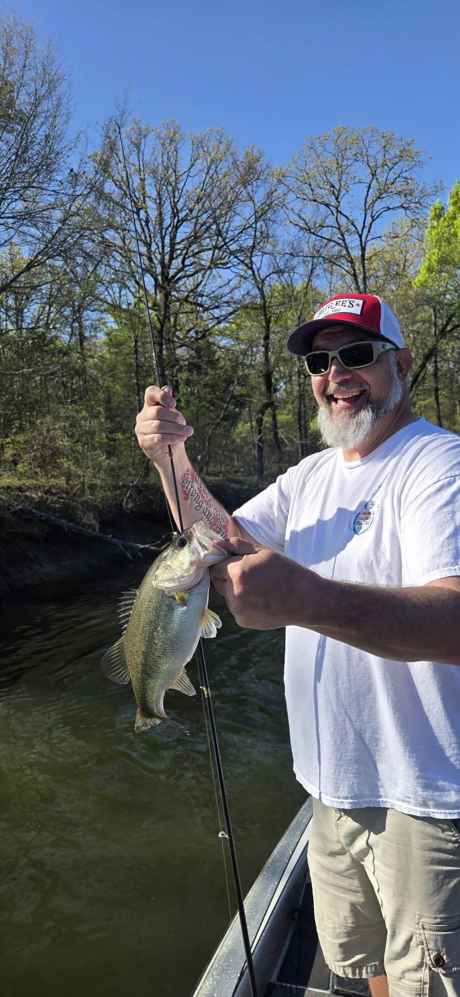 Angler holding freshly caught bass while fishing from boat in Quitman TX