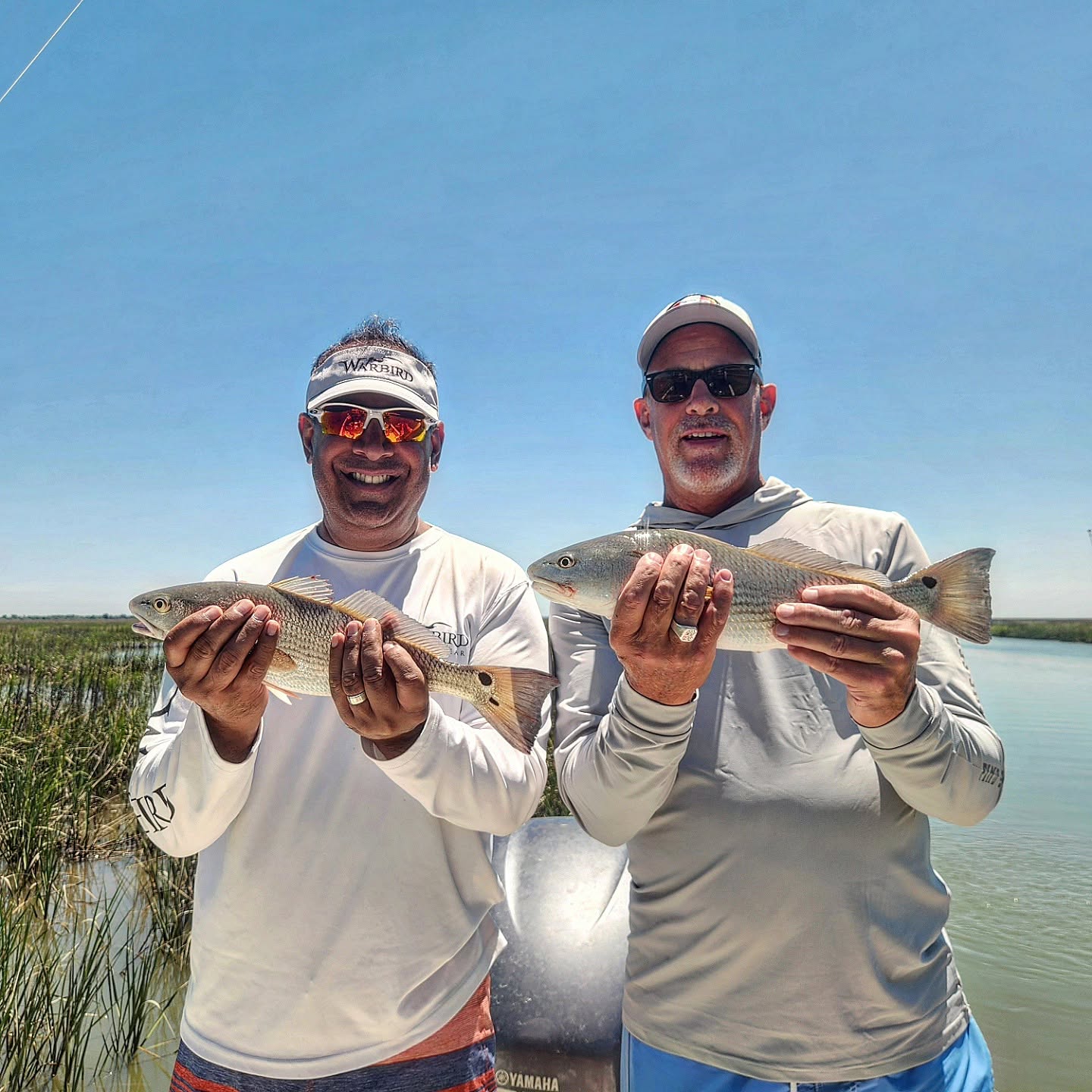 Two anglers holding redfish caught while fishing in Mount Pleasant SC