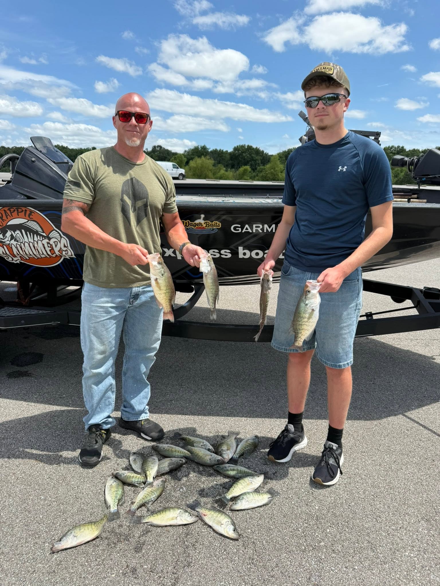 Successful fishing trip in Branson MO with multiple fish species caught and displayed on pavement near boat