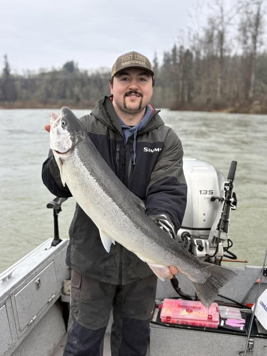 Angler holding large salmon catch on fishing boat in Toledo WA