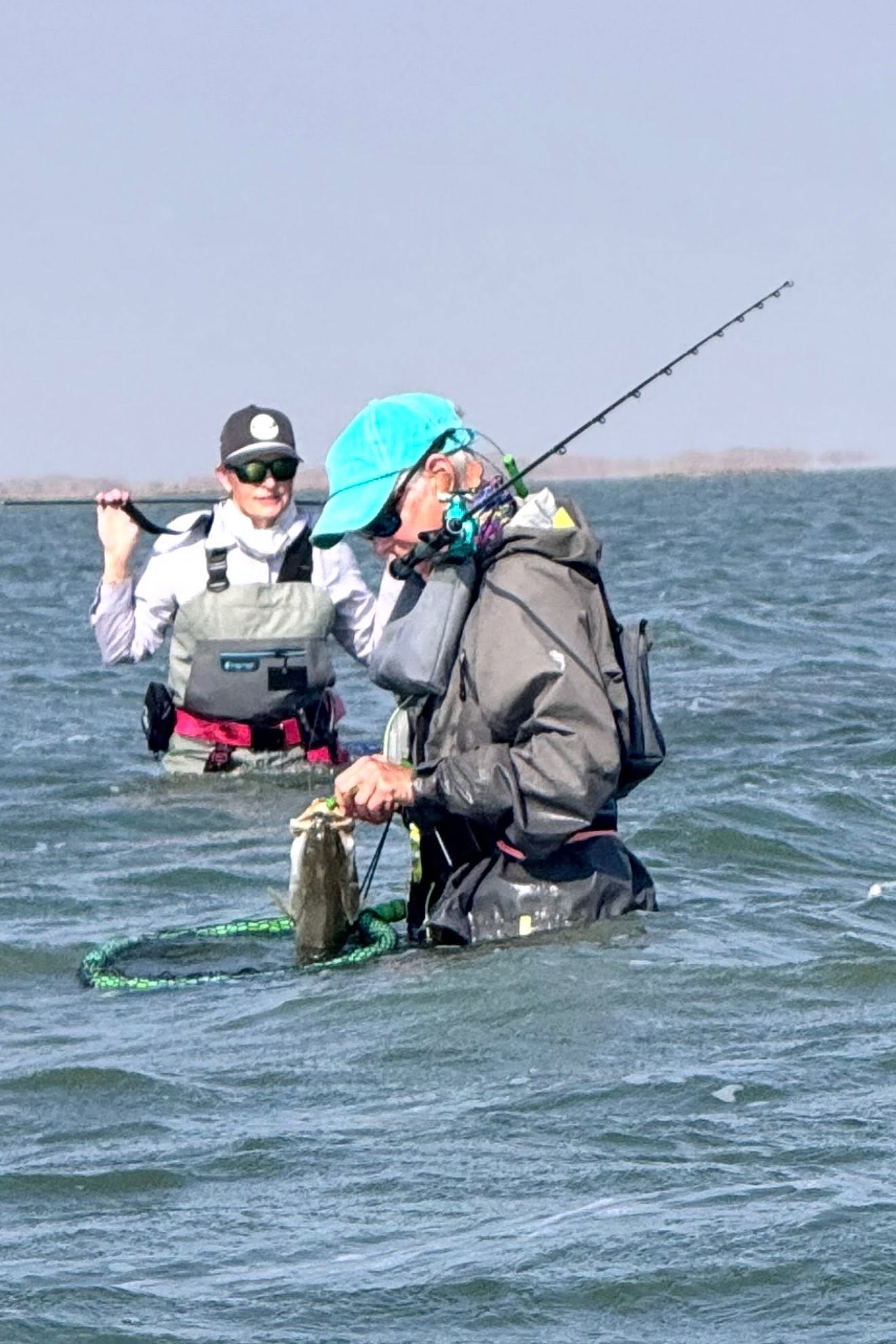 Anglers wade fishing in shallow water near Corpus Christi TX with fishing rod and net