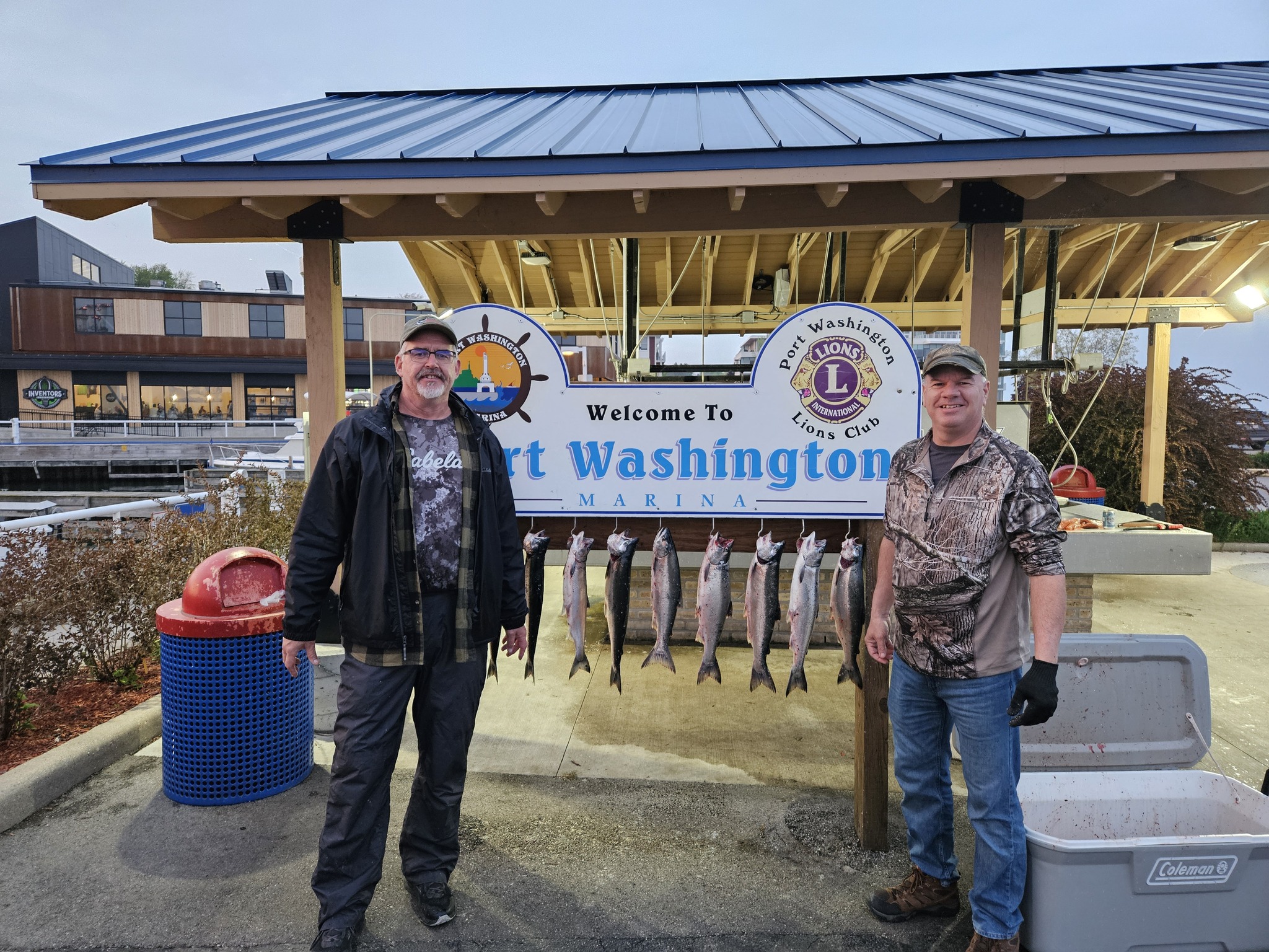 Two anglers displaying their catch of Pink Salmon, Chinook Salmon, and Coho Salmon at Port Washington WI marina