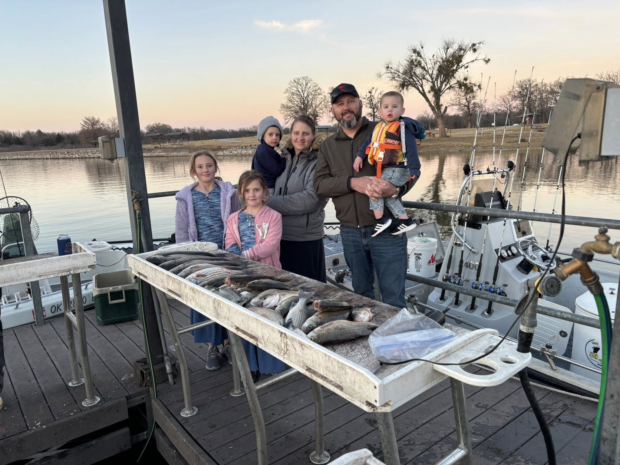 Family fishing trip in Kingston OK with large catch of fish displayed on boat cleaning table