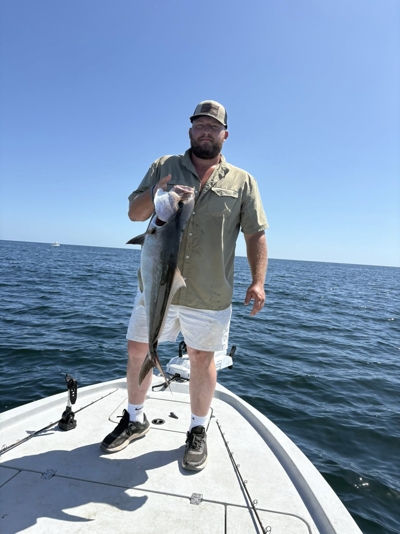 Angler holding caught fish on boat deck in Pensacola FL waters