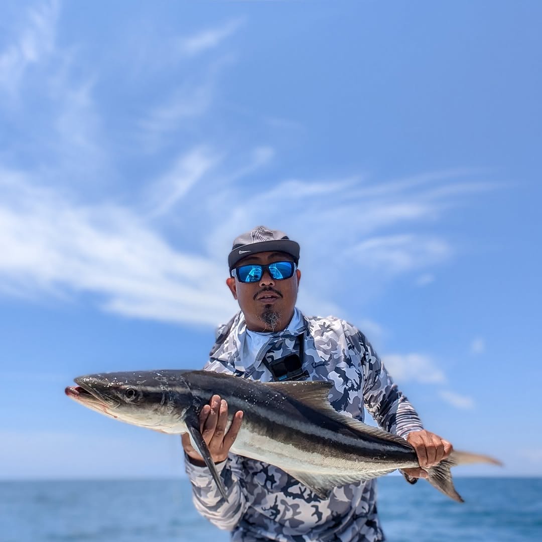 Fresh caught cobia held up against blue sky and ocean in St. Petersburg FL