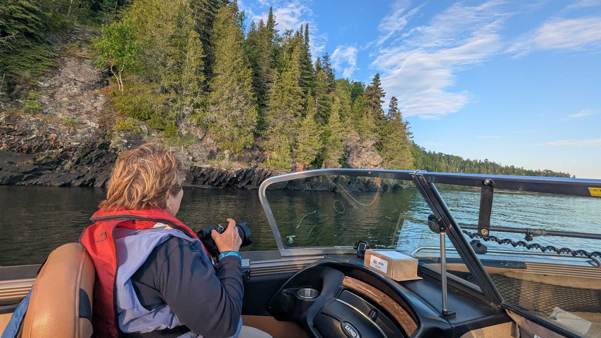 Fishing boat navigating through calm waters near forested shoreline in Nipigon Ontario