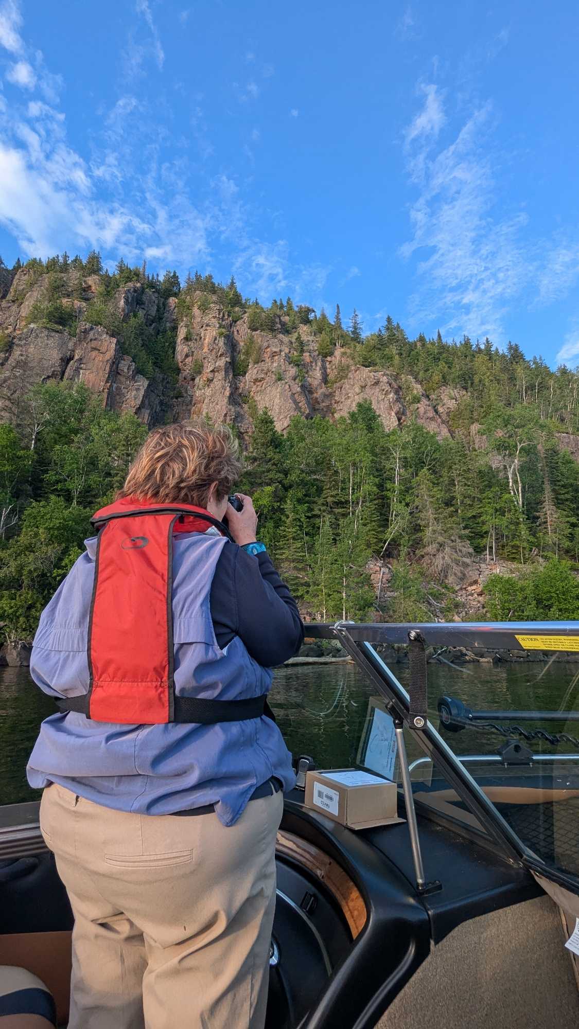 Fishing tour guide using binoculars to scout waters near rocky cliffs in Nipigon ON