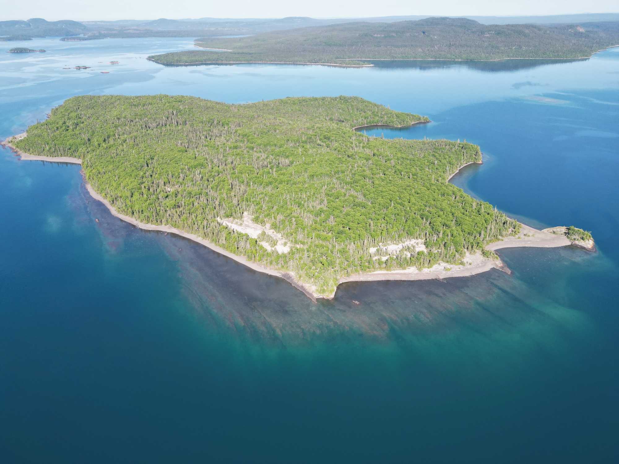 Aerial view of forested island surrounded by clear blue water in Nipigon Ontario, perfect fishing destination