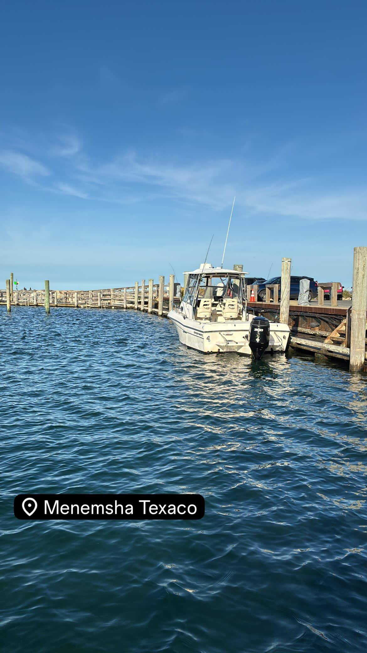 Fishing boat docked at wooden pier in Boston MA harbor with calm blue water