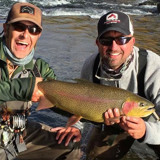 An angler holding a 15-inch rainbow trout in Taos
