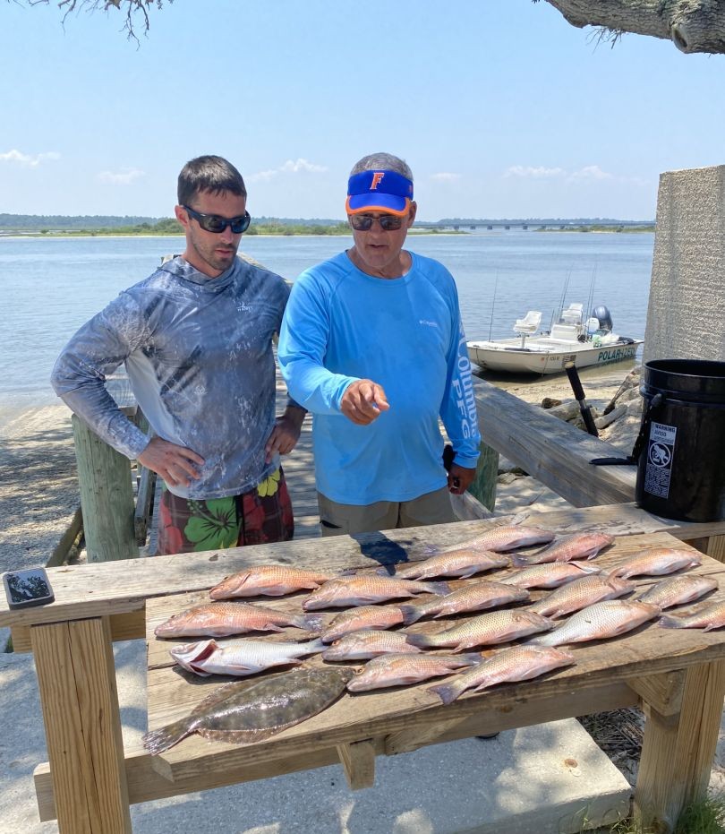 Fresh caught fish displayed on wooden cleaning table at St. Augustine FL fishing dock with boat in background
