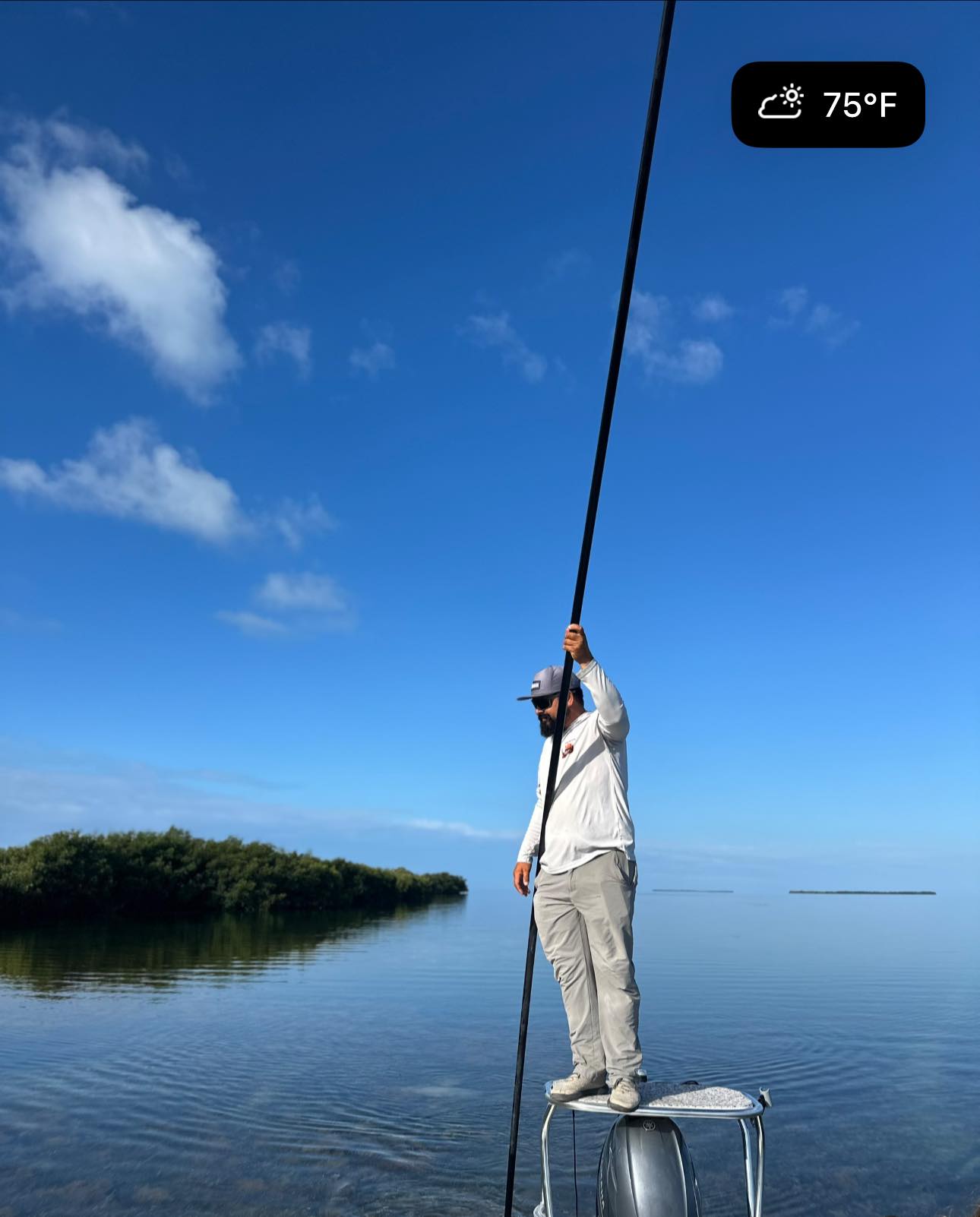 Angler standing on boat bow with fishing pole in shallow waters near mangroves in Islamorada FL