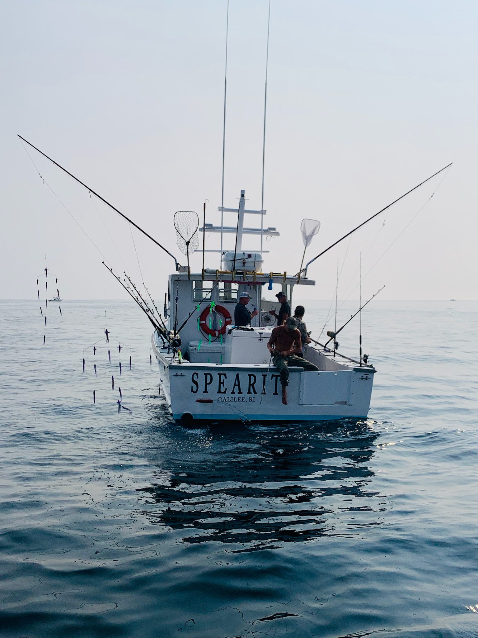 Fishing boat named Spearit from Galilee RI on calm ocean waters with multiple fishing rods extended