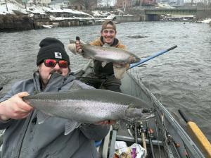 Two large fish caught during fishing trip in Oswego NY with boat and marina in background
