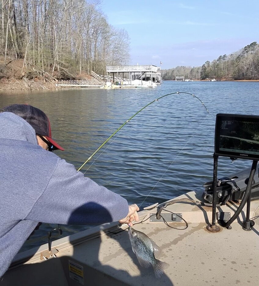 Fishing rod bent with fish hooked on lake near dock in Gainesville GA