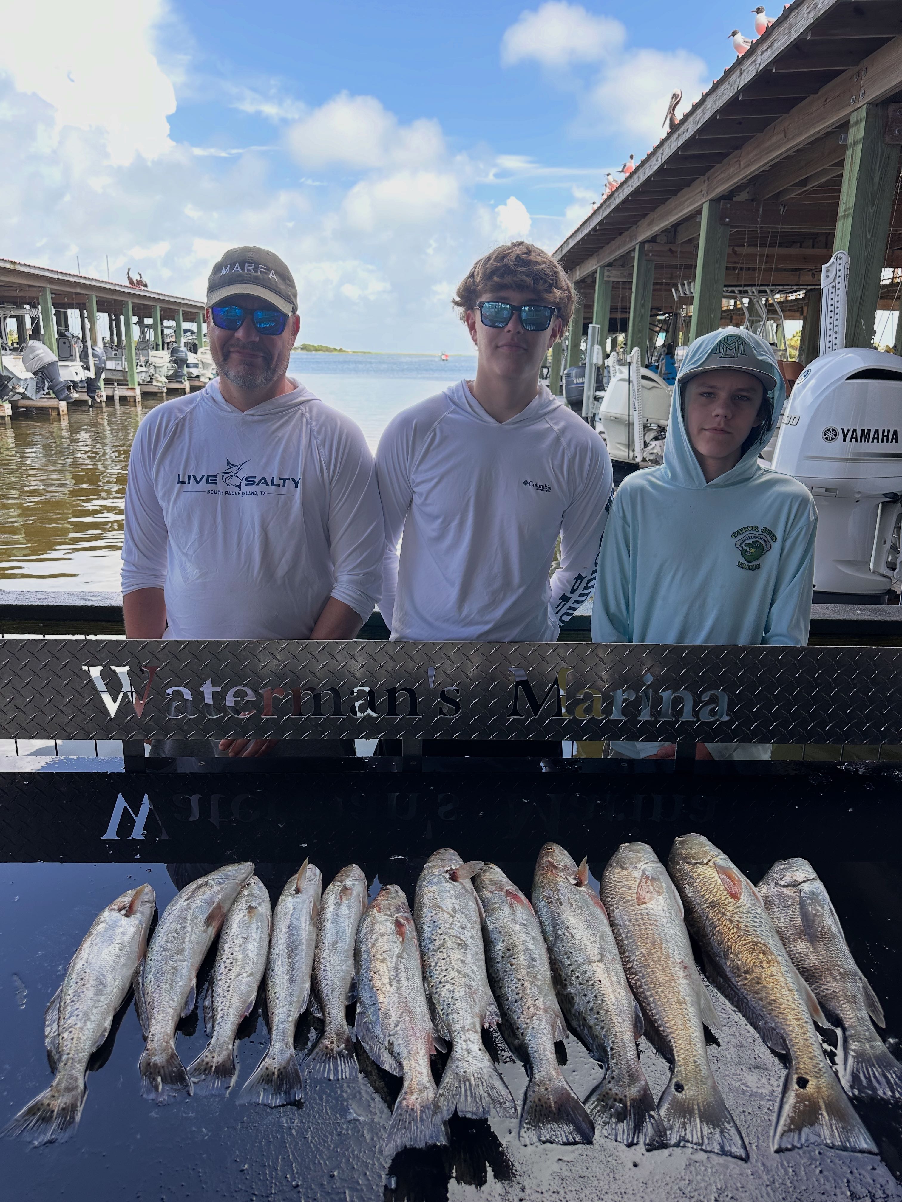 Successful fishing trip in Galveston TX showing caught speckled trout and redfish displayed on marina dock