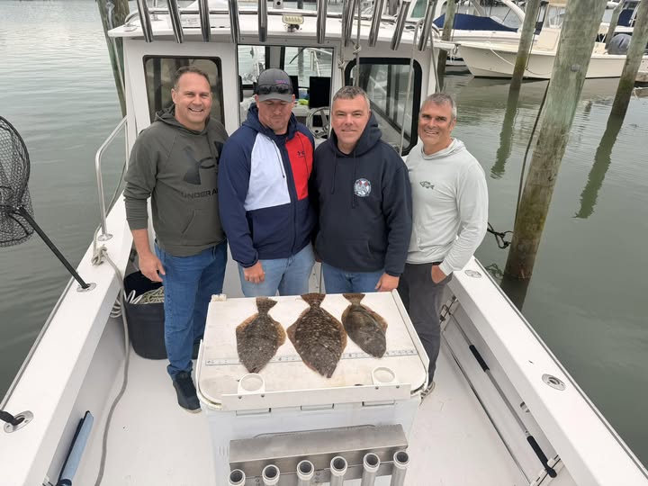Four anglers on fishing boat displaying three flounder catch in Brigantine NJ