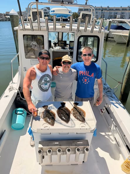 Three anglers displaying their catch of flounder on fishing boat in Brigantine NJ