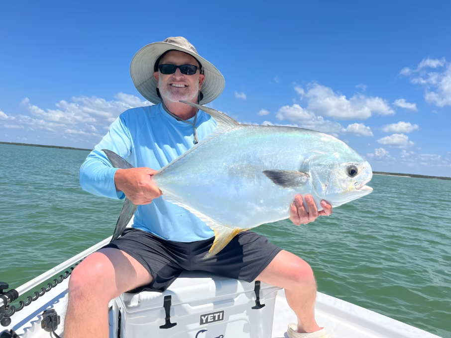 Angler holding large permit fish on boat in Naples FL waters