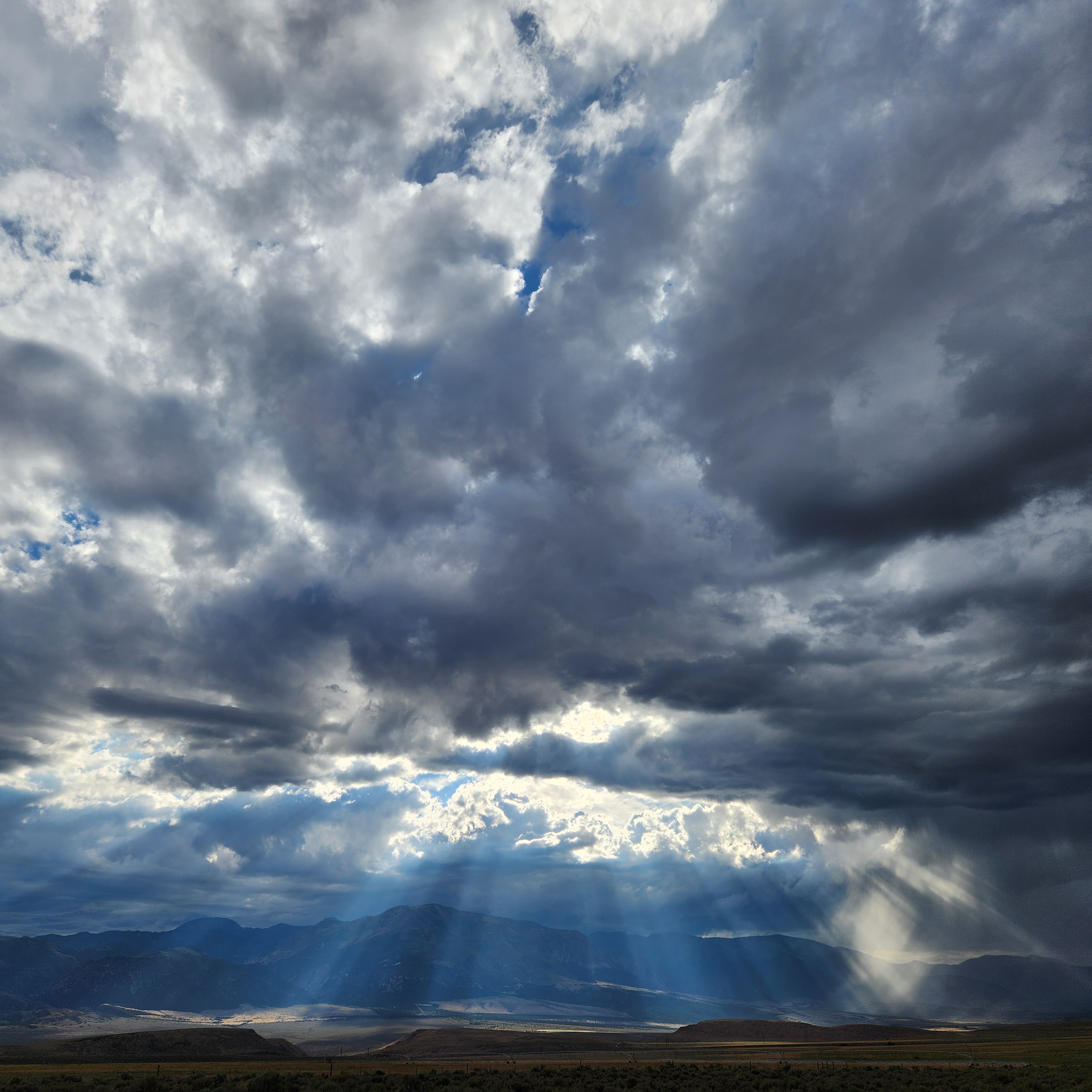 Dramatic storm clouds with sunbeams breaking through over mountainous landscape near Panguitch Utah