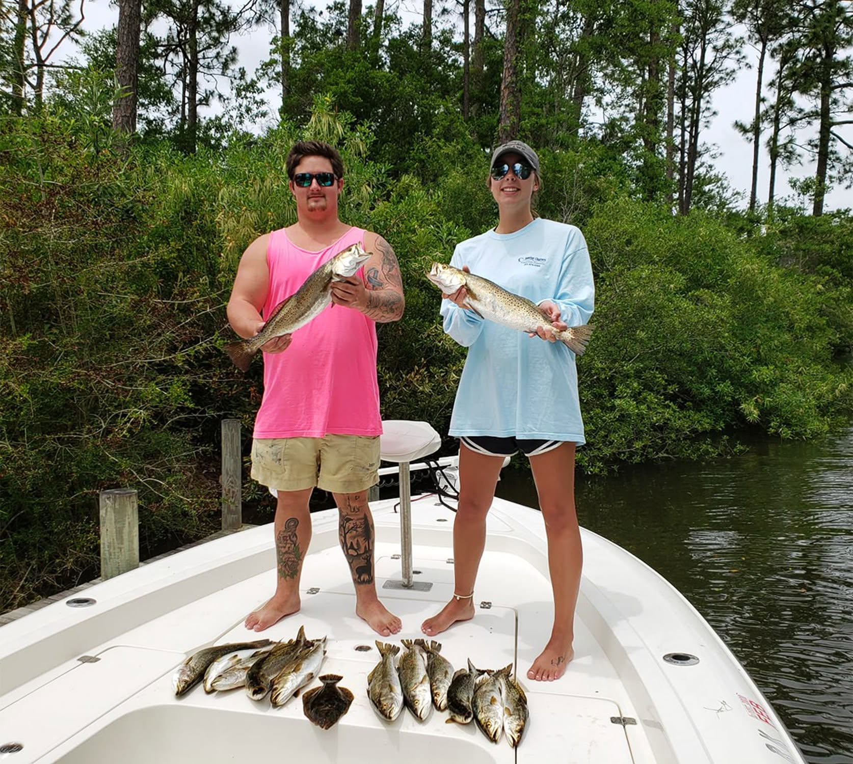 Successful speckled trout fishing trip on boat in Gulf Shores AL with mixed catch displayed on deck