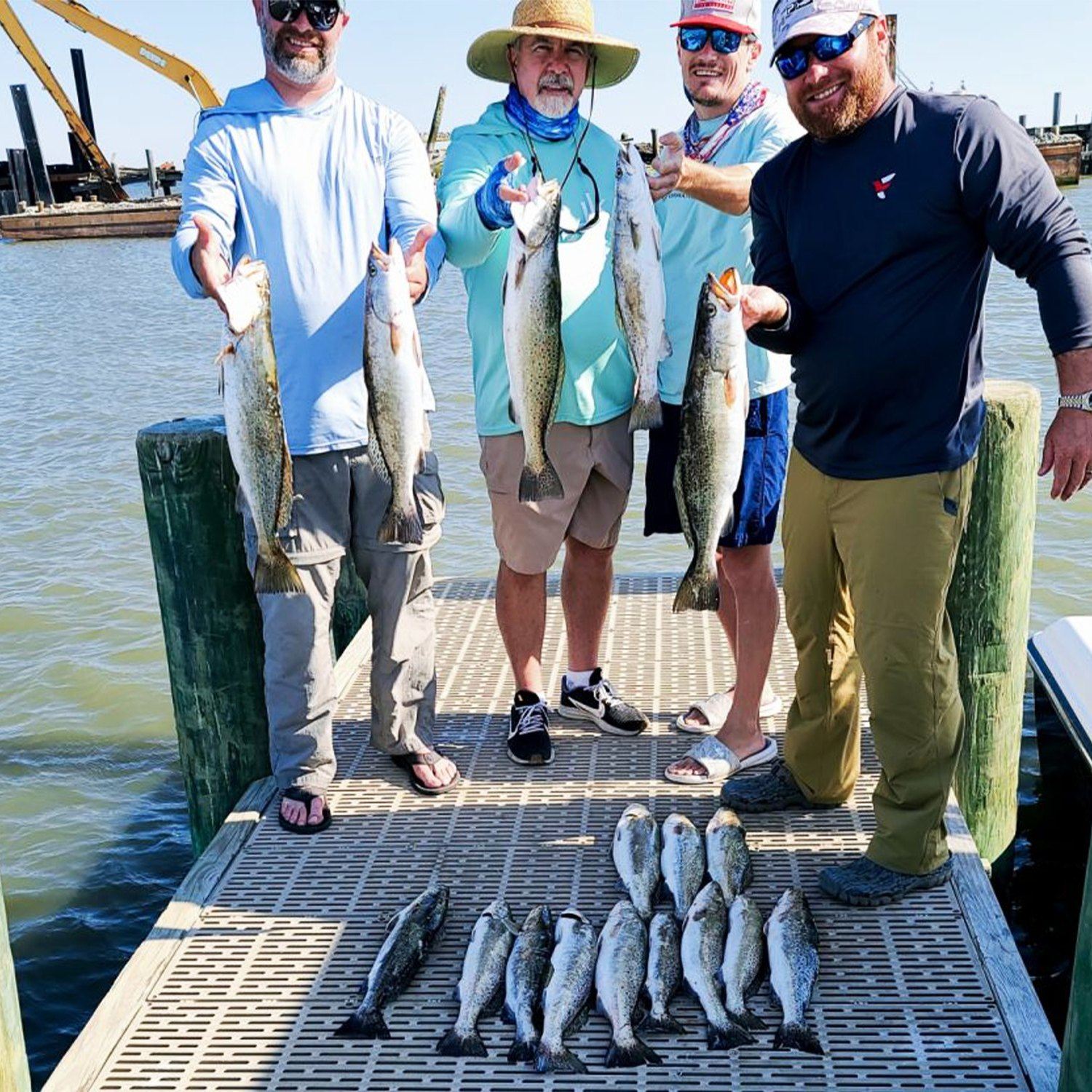 Successful speckled trout fishing trip in Gulf Shores AL with multiple fish displayed on dock